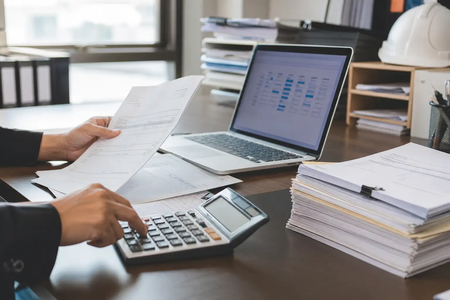 An AP clerk reviewing rental invoices, credit memos, and an aging report on a desk in an office setting.